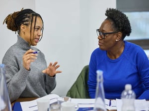 Two female attendees deep in discussion at a workshop