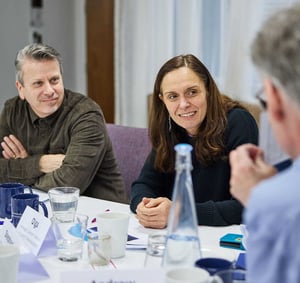 A man and a woman listening intently to a colleague