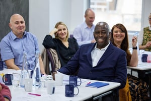 A vibrant team engages in a Strengthify workshop in a bright meeting room, collaborating to spark trust and creativity.